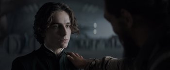 Movie still from “Dune” (2021), directed by Denis Villeneuve – A man is getting his hair cut by another man; Close Up shot, Over the shoulder angle