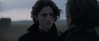 Movie still from “Dune” (2021), directed by Denis Villeneuve – A young man with long hair and a beard; Close Up shot, Over the shoulder angle