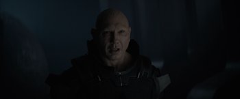 Movie still from “Dune” (2021), directed by Denis Villeneuve – A bald man with a knife in his mouth; Close Up shot, Over the shoulder angle