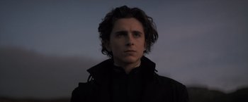 Movie still from “Dune” (2021), directed by Denis Villeneuve – A man with long hair is looking at the camera; Close Up shot, Low angle
