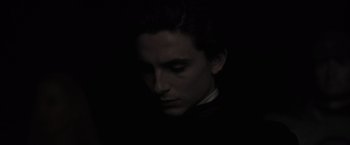Movie still from “Dune” (2021), directed by Denis Villeneuve – A man in a black shirt is looking at the camera; Close Up shot, High angle