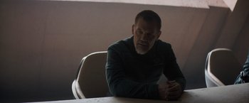 Movie still from “Dune” (2021), directed by Denis Villeneuve – A man sitting at a table with his hands crossed; Medium shot, Over the shoulder angle