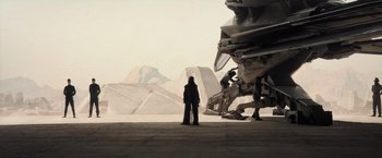 Movie still from “Dune” (2021), directed by Denis Villeneuve – A person standing in front of a building with mountains in the background; Extreme Wide shot, Low angle