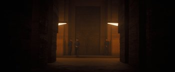 Movie still from “Dune” (2021), directed by Denis Villeneuve – Three men are standing in a dimly - lit room; Extreme Wide shot, Low angle