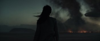 Movie still from “Dune” (2021), directed by Denis Villeneuve – A woman standing in front of a smoke filled sky at night; Extreme Wide shot, Low angle