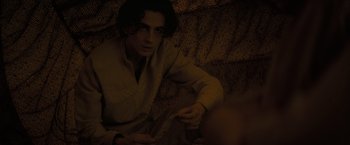 Movie still from “Dune” (2021), directed by Denis Villeneuve – A man sitting on top of a couch in the dark; Close Up shot, Over the shoulder angle