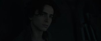 Movie still from “Dune” (2021), directed by Denis Villeneuve – A man with long dark hair is looking at the camera; Close Up shot, Low angle