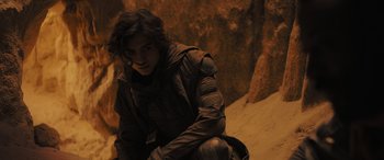 Movie still from “Dune” (2021), directed by Denis Villeneuve – A man sitting on the side of a cliff; Medium shot, High angle
