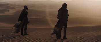 Movie still from “Dune” (2021), directed by Denis Villeneuve – A person standing in the sand with a bag; Wide shot, Low angle
