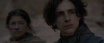 Movie still from “Dune” (2021), directed by Denis Villeneuve – A person with long dark hair; Close Up shot, Over the shoulder angle