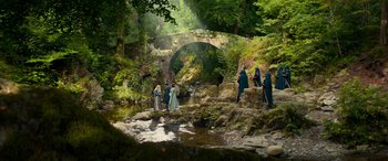 Movie still from “Dungeons & Dragons: Honor Among Thieves” (2023), directed by John Francis Daley – A group of people standing on rocks near a river; Extreme Wide shot, High angle