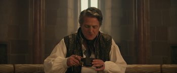 Movie still from “Dungeons & Dragons: Honor Among Thieves” (2023), directed by John Francis Daley – A man in a renaissance outfit holding a cup of coffee; Medium shot, Low angle