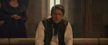 Movie still from “Dungeons & Dragons: Honor Among Thieves” (2023), directed by John Francis Daley – A man wearing a vest and a neck tie sitting in front of a window; Close Up shot, Over the shoulder angle