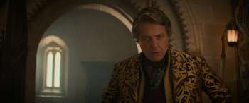 Movie still from “Dungeons & Dragons: Honor Among Thieves” (2023), directed by John Francis Daley – A man in a yellow and black jacket standing next to a wall; Close Up shot, Over the shoulder angle