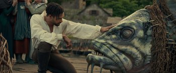 Movie still from “Dungeons & Dragons: Honor Among Thieves” (2023), directed by John Francis Daley – A man in a white shirt is touching the head of a dinosaur; Medium shot, Low angle