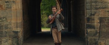 Movie still from “Dungeons & Dragons: Honor Among Thieves” (2023), directed by John Francis Daley – A man holding a guitar while standing in a tunnel; Wide shot, Low angle