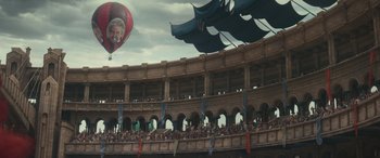 Movie still from “Dungeons & Dragons: Honor Among Thieves” (2023), directed by John Francis Daley – A crowd of people sitting in front of a large building; Extreme Wide shot, Low angle