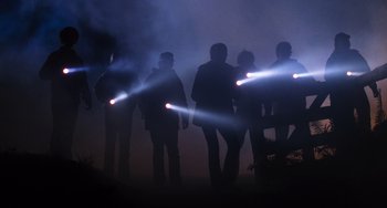 Movie still from “E.T. the Extra-Terrestrial” (1982), directed by Steven Spielberg – A group of people standing in the fog with lights on their heads; Wide shot, Low angle
