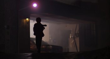 Movie still from “E.T. the Extra-Terrestrial” (1982), directed by Steven Spielberg – A person standing in the dark holding a gun; Wide shot, Low angle