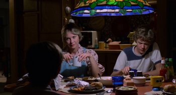 Movie still from “E.T. the Extra-Terrestrial” (1982), directed by Steven Spielberg – A group of people sitting at a table eating food; Medium shot, Over the shoulder angle