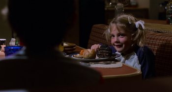 Movie still from “E.T. the Extra-Terrestrial” (1982), directed by Steven Spielberg – A little girl sitting at a table with a plate of food; Close Up shot, Over the shoulder angle