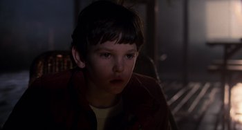 Movie still from “E.T. the Extra-Terrestrial” (1982), directed by Steven Spielberg – A young boy is sitting in a dark room; Close Up shot, Over the shoulder angle
