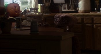 Movie still from “E.T. the Extra-Terrestrial” (1982), directed by Steven Spielberg – An image of an alien in a living room setting; Medium shot, Over the shoulder angle
