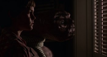 Movie still from “E.T. the Extra-Terrestrial” (1982), directed by Steven Spielberg – A young boy and an alien in a dark room; Close Up shot, Low angle