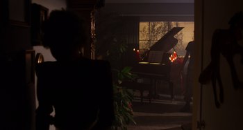 Movie still from “E.T. the Extra-Terrestrial” (1982), directed by Steven Spielberg – A person sitting in front of a piano in a living room; Wide shot, Over the shoulder angle