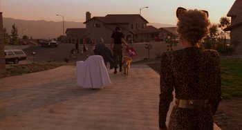 Movie still from “E.T. the Extra-Terrestrial” (1982), directed by Steven Spielberg – A group of people and a dog walking down a sidewalk; Wide shot, Over the shoulder angle