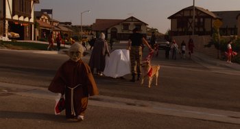 Movie still from “E.T. the Extra-Terrestrial” (1982), directed by Steven Spielberg – A group of people walking down a street with a dog; Wide shot, High angle