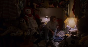 Movie still from “E.T. the Extra-Terrestrial” (1982), directed by Steven Spielberg – A woman sitting on a chair next to stuffed animals; Wide shot, High angle