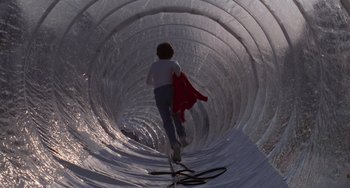 Movie still from “E.T. the Extra-Terrestrial” (1982), directed by Steven Spielberg – A person is walking in a tunnel with a red jacket; Wide shot, Low angle