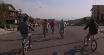 Movie still from “E.T. the Extra-Terrestrial” (1982), directed by Steven Spielberg – A group of bicyclists riding down a street; Wide shot, High angle