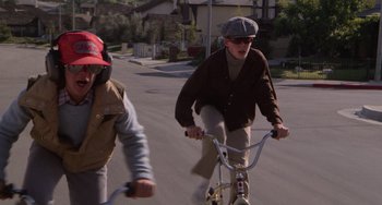 Movie still from “E.T. the Extra-Terrestrial” (1982), directed by Steven Spielberg – A man riding a bike down the middle of the street; Medium shot, High angle