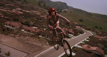 Movie still from “E.T. the Extra-Terrestrial” (1982), directed by Steven Spielberg – A man riding a bike down a ramp over a street; Wide shot, High angle