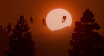 Movie still from “E.T. the Extra-Terrestrial” (1982), directed by Steven Spielberg – A group of people flying through the air while riding skatebaords; Extreme Wide shot, Low angle