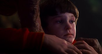 Movie still from “E.T. the Extra-Terrestrial” (1982), directed by Steven Spielberg – A young boy is looking at the camera with a hand on his shoulder; Close Up shot, Low angle