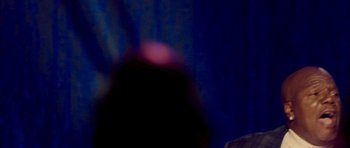 Movie still from “Chappelle's Home Team - Earthquake: Legendary” (2022), directed by Stan Lathan – A blurry image of a person in a dark room; Extreme Close Up shot, Over the shoulder angle