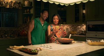 Movie still from “Easter Sunday” (2022), directed by Jay Chandrasekhar – A man and a woman in a kitchen taking a picture with a cell phone; Medium shot, Overhead angle