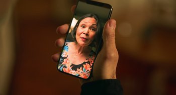 Movie still from “Easter Sunday” (2022), directed by Jay Chandrasekhar – A person holding a cell phone in their hand; Extreme Close Up shot, Over the shoulder angle