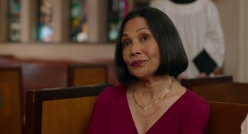 Movie still from “Easter Sunday” (2022), directed by Jay Chandrasekhar – An older woman sitting on a bench in front of a stained glass window; Close Up shot, Over the shoulder angle