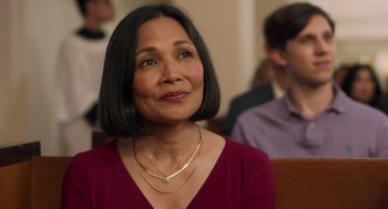 Movie still from “Easter Sunday” (2022), directed by Jay Chandrasekhar – An older woman wearing a red shirt and a gold necklace; Close Up shot, Over the shoulder angle
