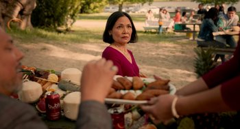 Movie still from “Easter Sunday” (2022), directed by Jay Chandrasekhar – A woman sitting in front of a plate of food; Medium shot, Over the shoulder angle