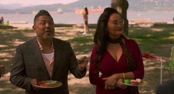Movie still from “Easter Sunday” (2022), directed by Jay Chandrasekhar – A man and a woman standing next to each other holding plates; Medium shot, High angle