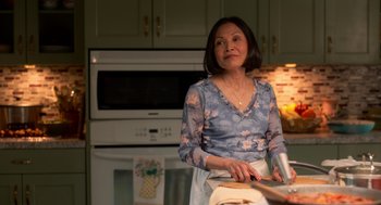 Movie still from “Easter Sunday” (2022), directed by Jay Chandrasekhar – An older woman standing in a kitchen preparing food; Medium shot, Low angle