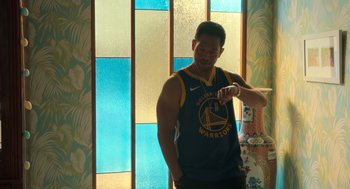 Movie still from “Easter Sunday” (2022), directed by Jay Chandrasekhar – A man standing in front of a stained glass window looking at his watch; Medium shot, Low angle