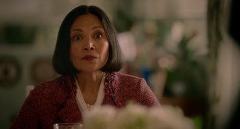 Movie still from “Easter Sunday” (2022), directed by Jay Chandrasekhar – An older woman sitting in front of a table with flowers; Close Up shot, Over the shoulder angle