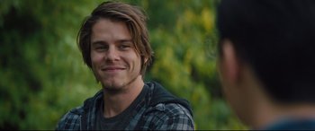 Movie still from “A Dog's Journey” (2019), directed by Gail Mancuso – A young man smiling for the camera in front of trees; Close Up shot, Over the shoulder angle