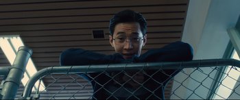 Movie still from “A Dog's Journey” (2019), directed by Gail Mancuso – A man with glasses leaning on a metal fence; Close Up shot, Low angle